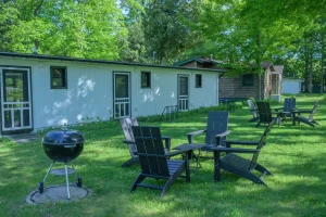 Black Adirondack chairs and a grill sit on the lawn at our places to stay near sleeping bear dunes.