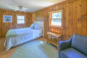 A bed with blue bedding sits in a wood-paneled room at these places to stay near Sleeping Bear Dunes.